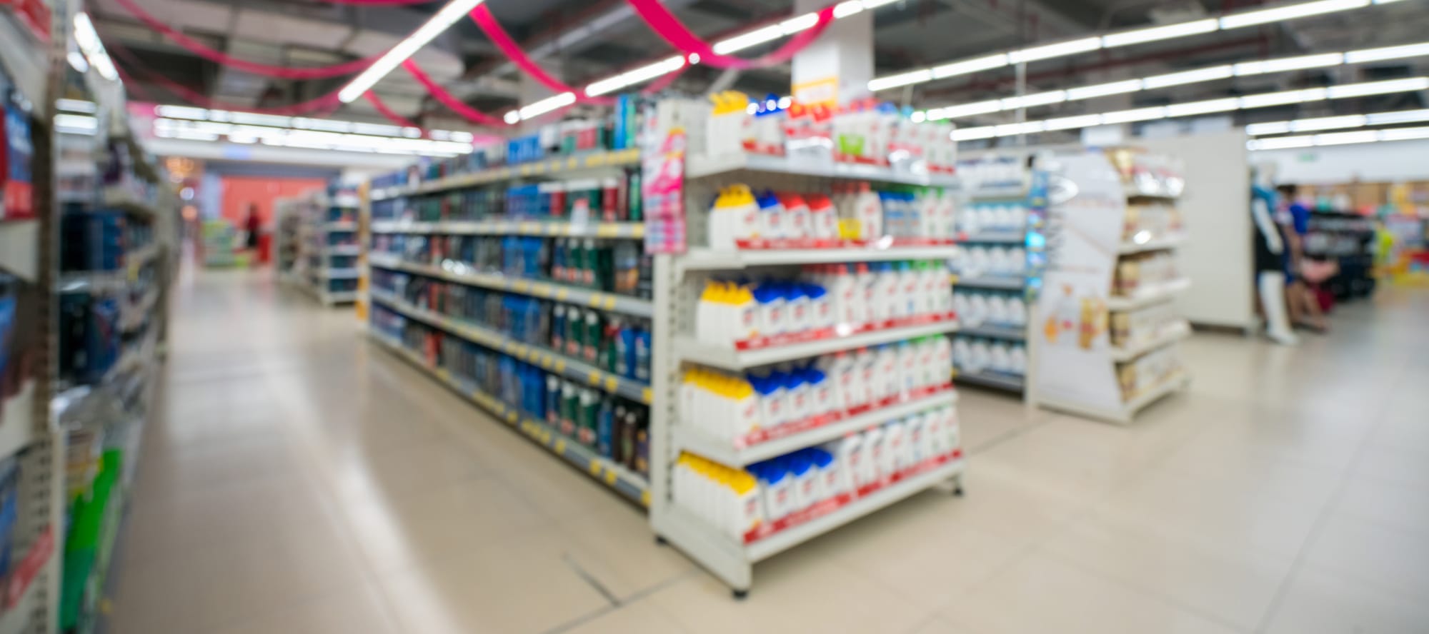 Retail store blurred background with colorful shelves and unrecognizable customers.