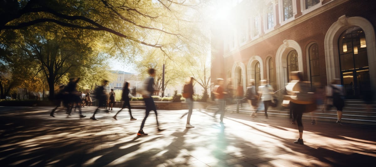 Crowd of students walking through a college campus on a sunny day, motion blur