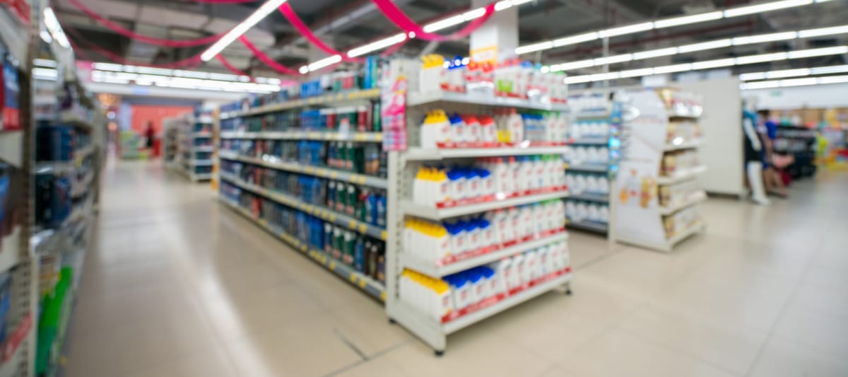 Retail store blurred background with colorful shelves and unrecognizable customers.