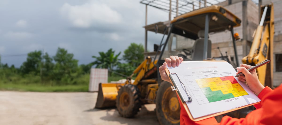 Operation supervisor using ballpoint pen to mark on a risk assessment form inspecting a backhoe machine